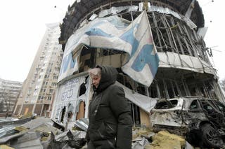 युक्रेनमधील रशियन-नियंत्रित डोनेस्कमध्ये गोळीबारामुळे नुकसान झालेल्या दुकानाजवळून एक महिला चालत आहे.